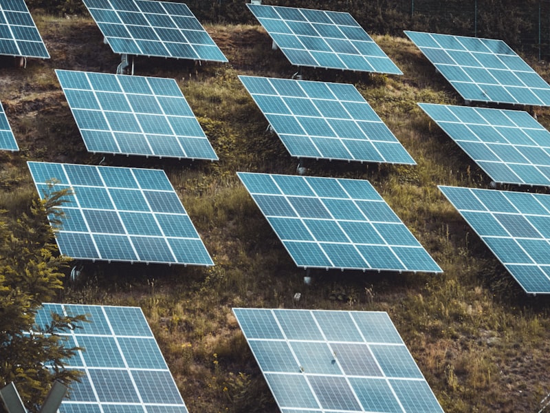 Solar panels mounted on the sloped metal roof of a rural barn beside a farmhouse